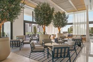 a lobby with tables and chairs and trees at Palace Dubai Creek Harbour in Dubai
