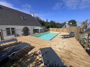a wooden deck with a swimming pool and a house at Ty gouldri in Perros-Guirec