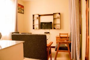 a living room with two chairs and a television at Hecasa Apartments in Arusha