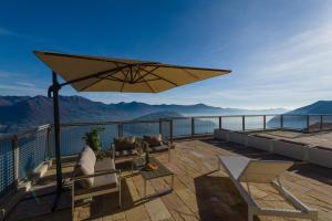 a patio with chairs and an umbrella on a balcony at EnjoyIseoLake - Lake View Paradise in Parzanica