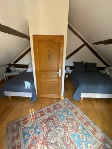 a attic bedroom with two beds and a door at Le Logis Du Regisseur in Charny
