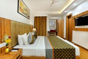 a hotel room with a bed and a tv at Rahitya Premier in New Delhi