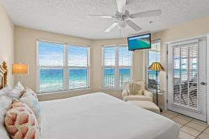 a bedroom with a bed and a tv and windows at The Palms #601 in Fort Walton Beach