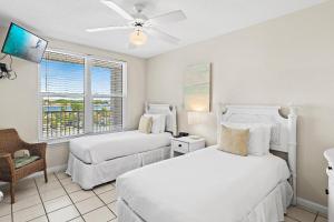 a bedroom with two beds and a chair and a window at The Palms #601 in Fort Walton Beach +60 photos