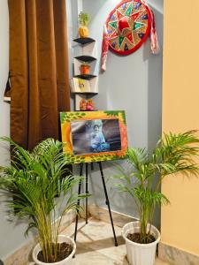 a painting on a easel in a room with two plants at Jonaki Aalay-Cozy and Budget Stay-Ulubari in Guwahati