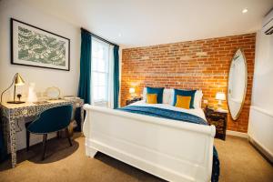 a bedroom with a white bed and a brick wall at Banyers House in Royston