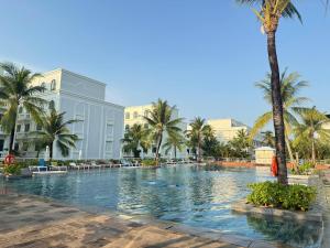 a large swimming pool with palm trees and buildings at LALU Hotel in Phú Quốc +16 photos