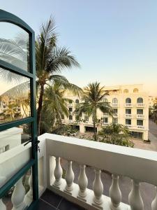 a balcony with a view of a building and palm trees at LALU Hotel in Phú Quốc