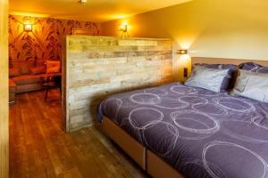 a bedroom with a large bed with a wooden wall at lignely in Durbuy
