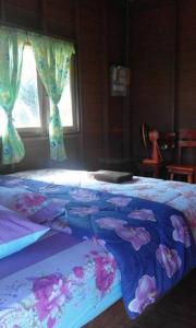 a bed with a blue comforter with flowers on it at Lungcha Homestay in Sam Roi Yot