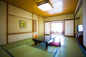 a living room with a table and a tv at Hotel Sekitei in Fuefuki