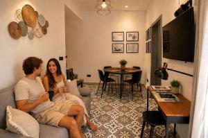 a man and woman sitting on a couch in a living room at Iris -Paola Modern Townhouse in Paola