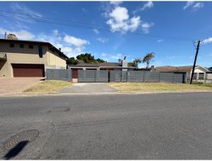 an empty street in front of a house with a fence at Joys House in Cape Town