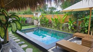 a swimming pool in a yard with two chairs and an umbrella at Amed Saïta Villas in Amed