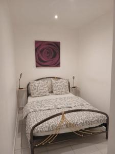 a bed in a white room with a painting on the wall at Le Lohan in Port-Saint-Louis-du-Rhône
