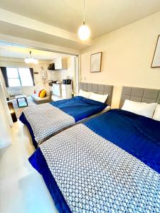 two beds in a bedroom with blue sheets at v大通401 札幌駅近 大通公園市電駅前 北海道観光旅行 家族にもお勧め すすきのへも直通 スーペリアルーム最大7名 11歳まで子供無料チェックアウト11時 in Sapporo