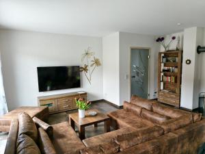 a living room with brown couches and a flat screen tv at Haus Lütti in Glowe