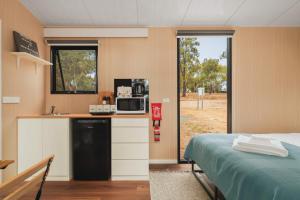 a room with a bed and a kitchen with a microwave at Kiara By Tiny Away in Stawell