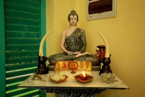 a statue of a woman sitting on a table with a candle at Funky Monkey Surfhostel Hiriketiya in Hiriketiya +12 photos