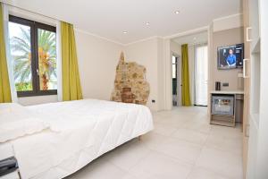 a bedroom with a large white bed and a fireplace at Hotel Corallo New in Muravera