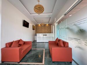 a living room with red furniture and a chandelier at Hotel Aura Inn in Dehu