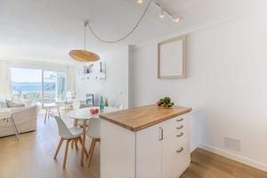 a kitchen with white cabinets and a dining room with a table at Apartment Vida Sana by Sealand Villas in Alcudia +18 photos