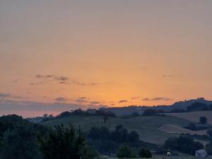 a sunset over the hills with trees in the foreground at Orchard House North in Pergola
