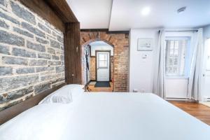 a bedroom with a brick wall and a white bed at Near the Ferry - Studio de charme in Lévis