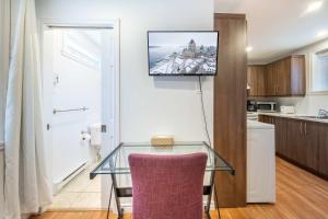 a glass table in a kitchen with a tv on the wall at Near the Ferry - Studio de charme in Lévis +21 photos