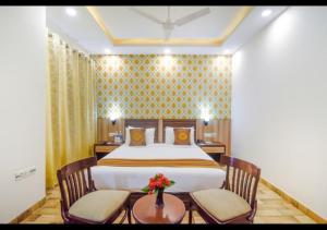 a bedroom with a bed with two chairs and a table at Royal Residence Golf Course Road in Gurgaon +2 photos