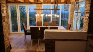 a dining room with a table and chairs and windows at Danube Escape with Jacuzzi, Pool & Spacious Yard by Destination GREEN Croatia in Bogaljevci