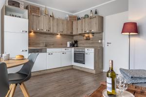 a kitchen with white cabinets and a table with a bottle of wine at Mühlenstraße 19 Ferienwohnung 50227 in Carolinensiel