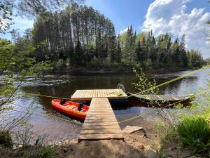 a boat is tied to a dock on a river at Spa & River - Hidden chalet - Chalet cache in Saint-Alexis-des-Monts