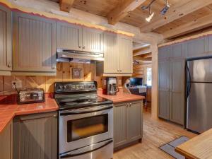 a kitchen with stainless steel appliances and wooden cabinets at Spa & River - Hidden chalet - Chalet cache in Saint-Alexis-des-Monts +21 photos