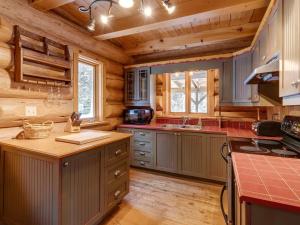 a large kitchen with wooden walls and wooden floors at Spa & River - Hidden chalet - Chalet cache in Saint-Alexis-des-Monts