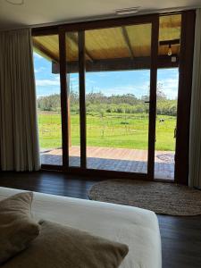 a bedroom with a view of a field through a window at O REFUXIO DOS CEBREIROS in Mazaricos