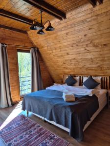 a bedroom with a bed and a wooden wall at Twin Cabins / Cabanele Gemene in Suceava
