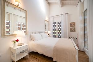 a white bedroom with a white bed and a mirror at Il fienile del borgo in Prato