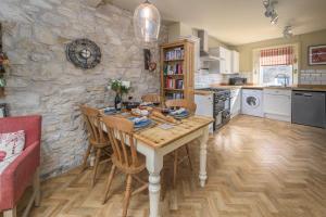 a kitchen with a table and chairs and a stone wall at 2 Bed in Warkworth oc-coq95 in Warkworth