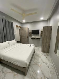 a bedroom with a large white bed and a television at Hotel HiCity Comfort Near DLF Cyber City & AIG Hospital in Hyderabad