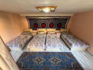 a bedroom with two beds and a rug at Hotel & Hostel Siyob Samarkand in Samarkand