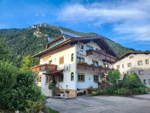 a large building with a mountain in the background at am Mühlbach - Ferienwohnungen Luttinger in Bichlbach