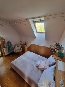 a attic bedroom with a bed and a window at Bámbi Apartman in Harsány