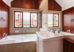 a bathroom with a tub and a sink and two windows at Waterkloof Apartments in Pretoria +70 photos