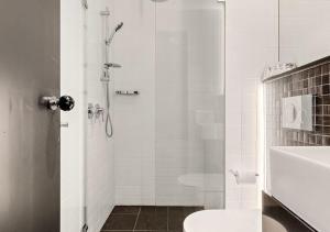 a bathroom with a shower with a toilet and a sink at Spice Serviced Apartments in Sydney