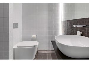a bathroom with a white toilet and a sink at Spice Serviced Apartments in Sydney +5 photos
