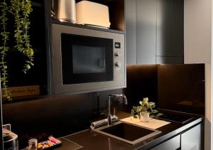 a kitchen with a sink and a microwave at Spice Serviced Apartments in Sydney