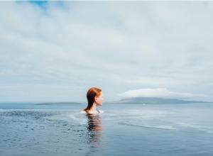 a woman standing in the water in the ocean at Hotel Føroyar in Tórshavn