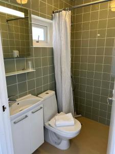a bathroom with a toilet and a sink and a mirror at Hotel Villum in Sandvig +13 photos