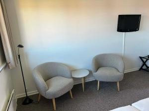 two chairs and a table in a room with a tv at Hotel Villum in Sandvig